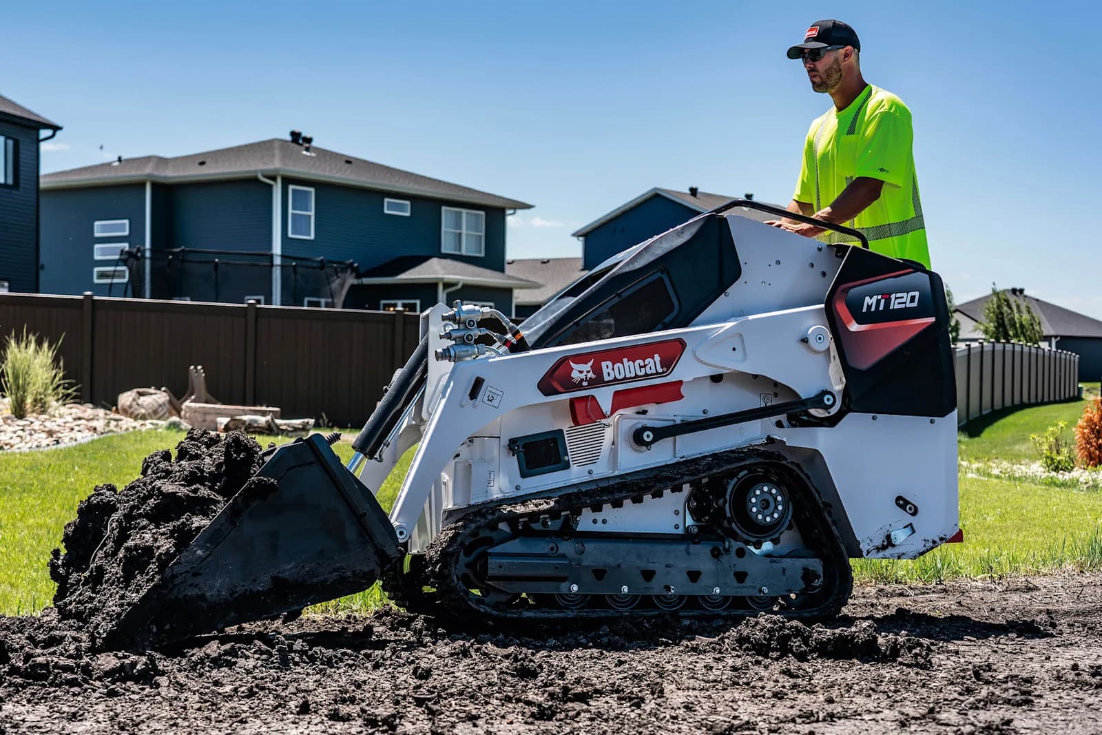 Bobcat MT-120 mini skid steer loading soil in a residential Jacksonville backyard